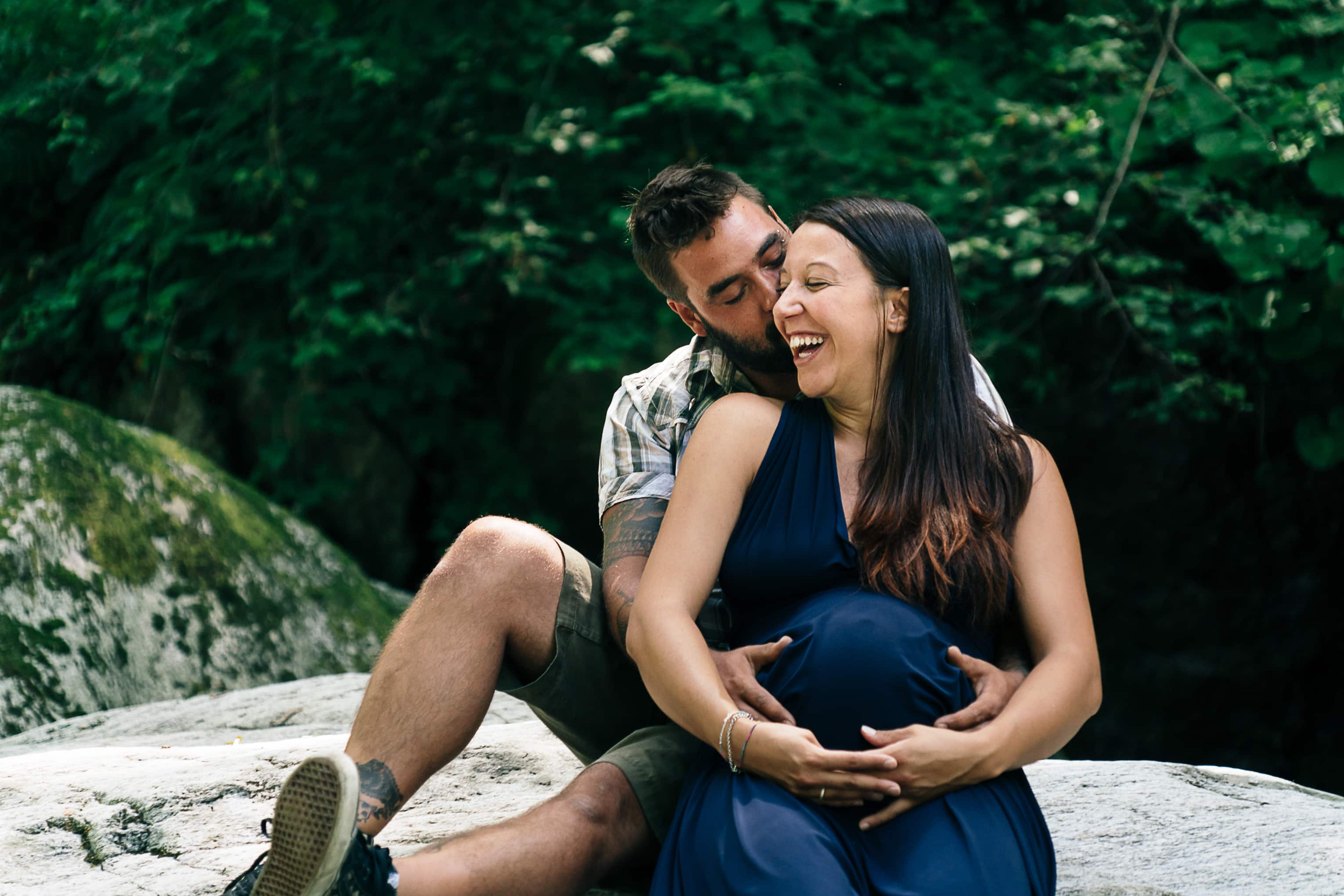 Sich umarmendes Paar auf einem Felsen in der Mitte des San Giovanni, Schwangerschaftsshooting in Maccagno