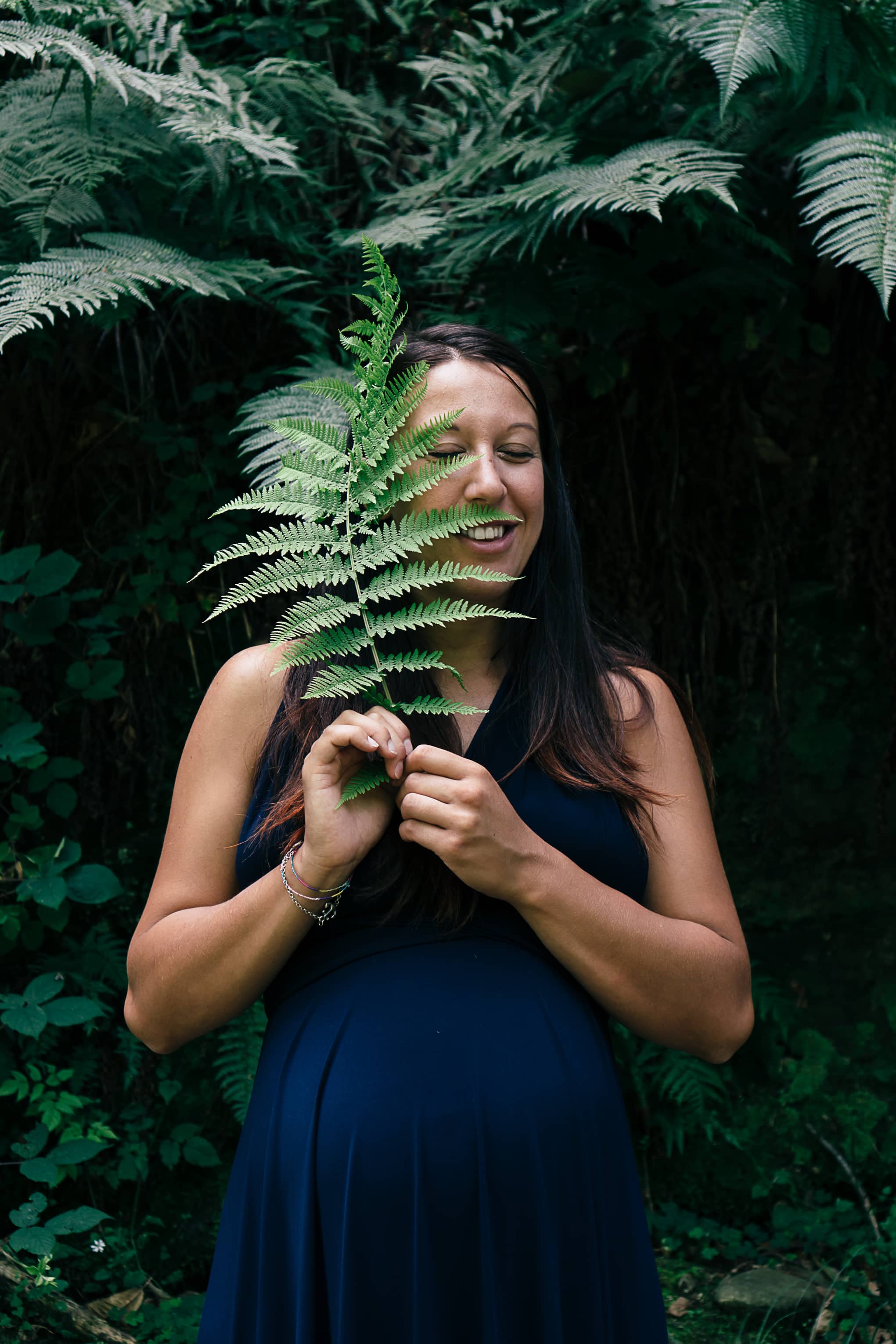 Valeria, versteckt hinter einem Farnblatt, während des Schwangerschaftshootings