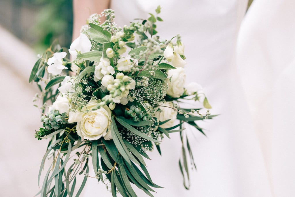 Der Brautstrauß mit silbergrauem Grün und weißen Blumen, locker gebunden. Hochzeitsfotografie.