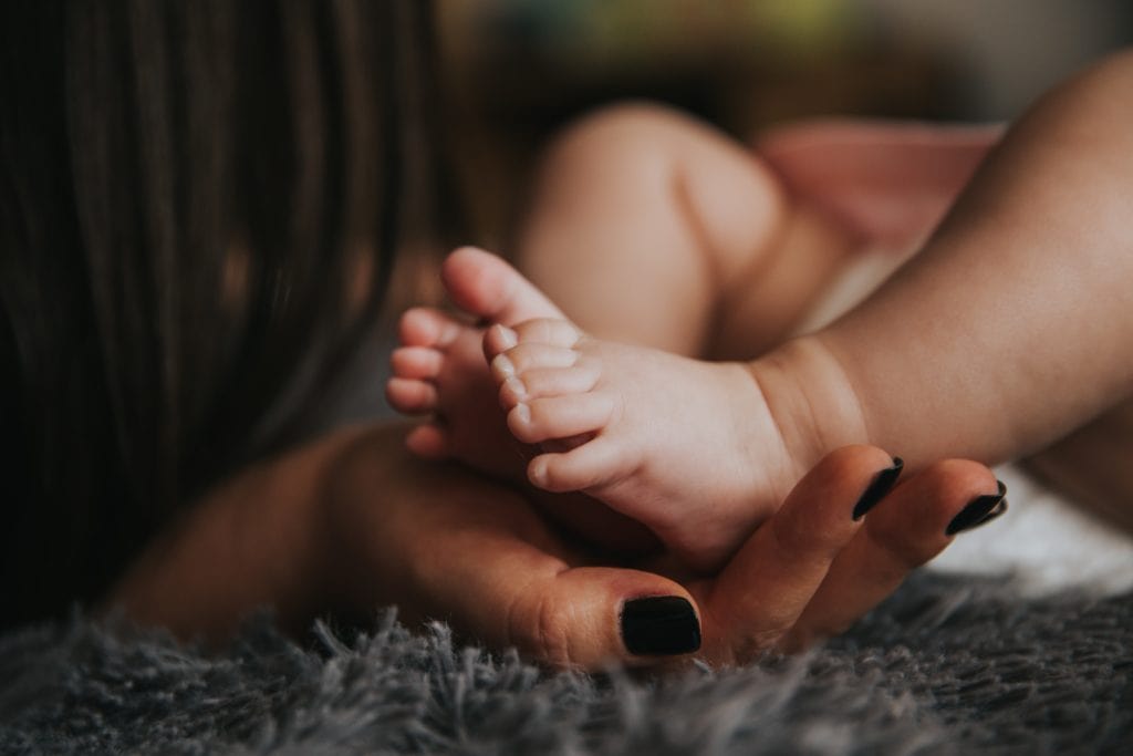 Babyfoto: Kleine Babyfüße in den Händen einer Frau