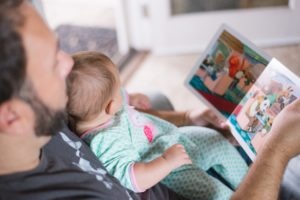 Klassisches Babyfoto: Vater liest seinem Kind vor.