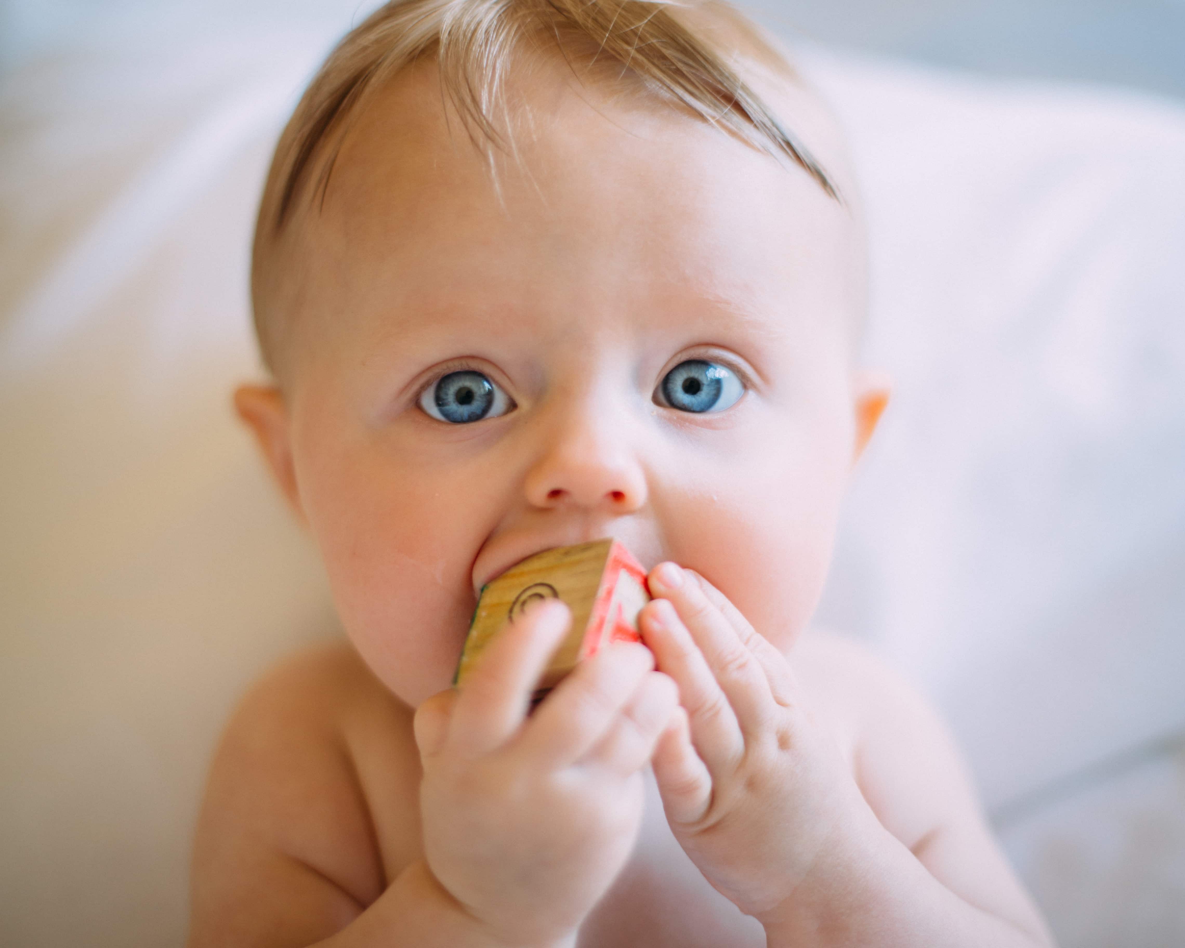 Baby mit Holzwürfel im Mund