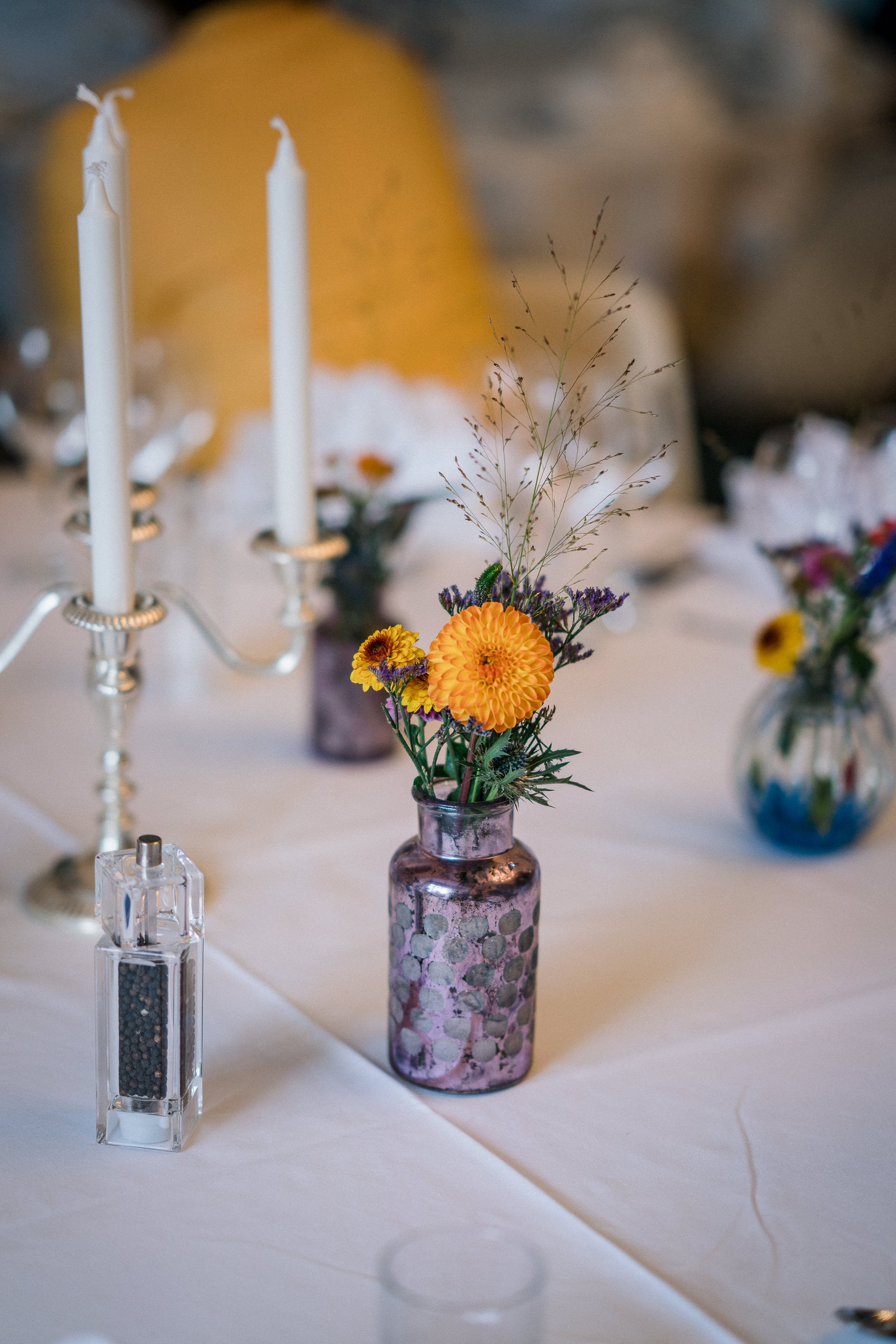 Dahlien und Disteln in einer lilafarbenen Vintagevase als Hochzeitsdekoration.